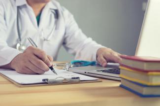 doctor writing on clipboard