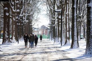 Photo of people walking on a snowy campus.